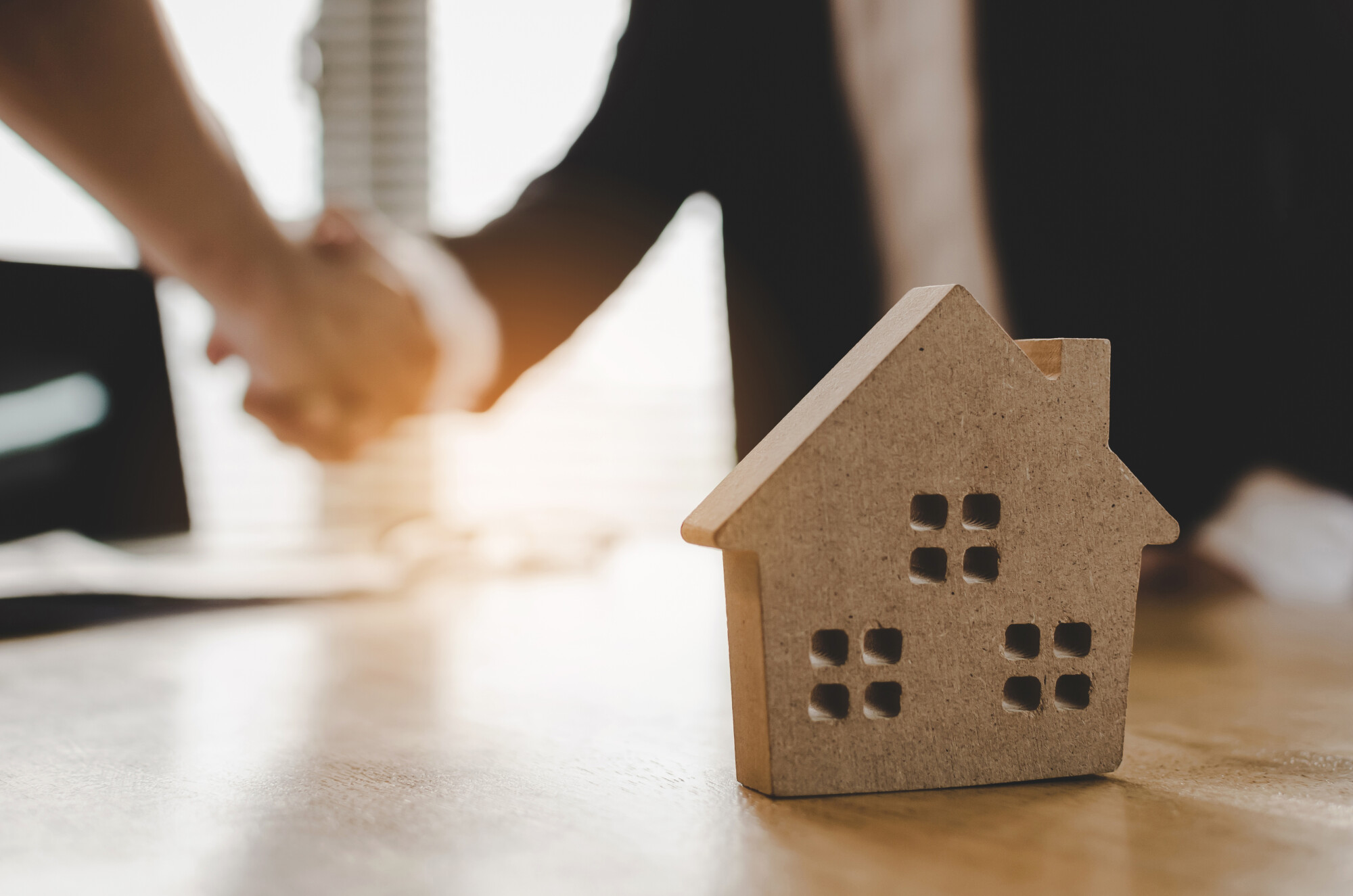 real estate broker manager hand shake to customer after signing contract for buying house in estate agent office behind House model, investment, home loan contract, buy and sell house concept