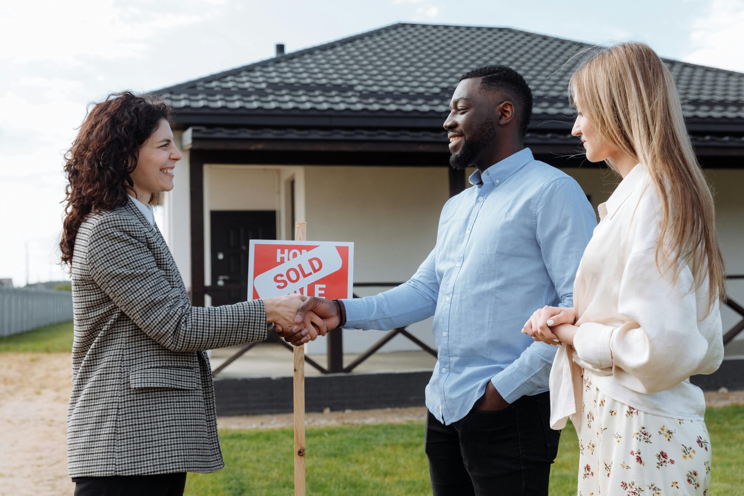 A smiling couple receiving the keys to their new home from a real estate agent, symbolizing the successful completion of their home purchase.